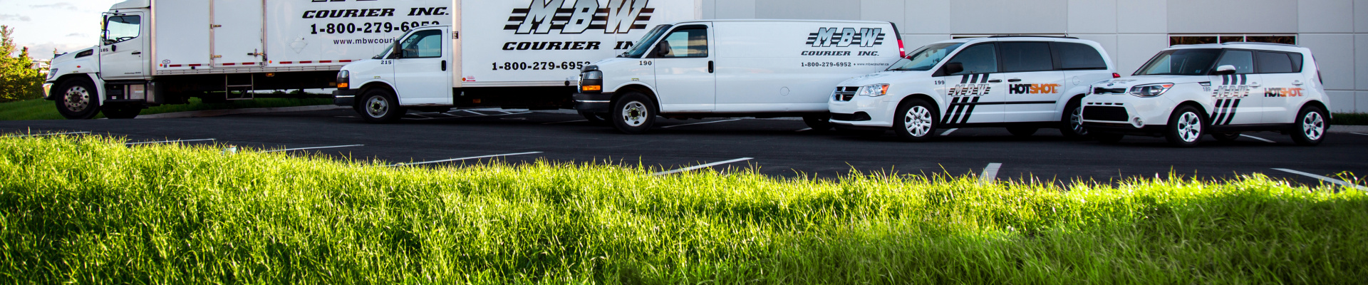 A line up of different size MBW vehicles in front of the MBW office.