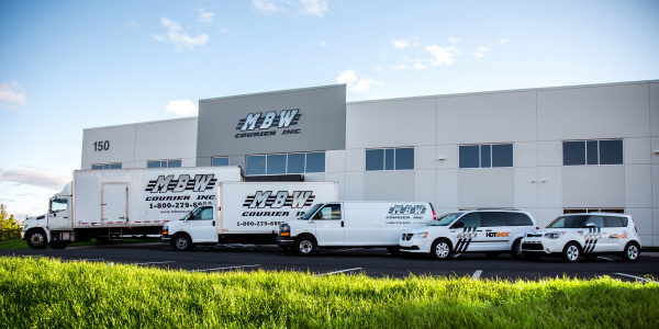 A line up of different size MBW vehicles in front of the MBW office.